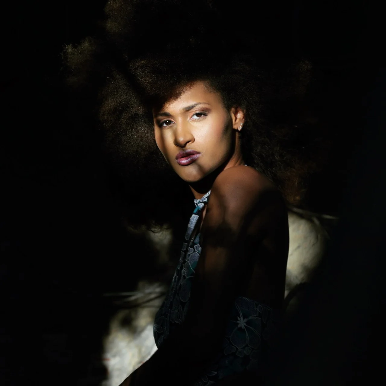 Retrato de moda con luz sobre el rostro y fondo en sombra.
