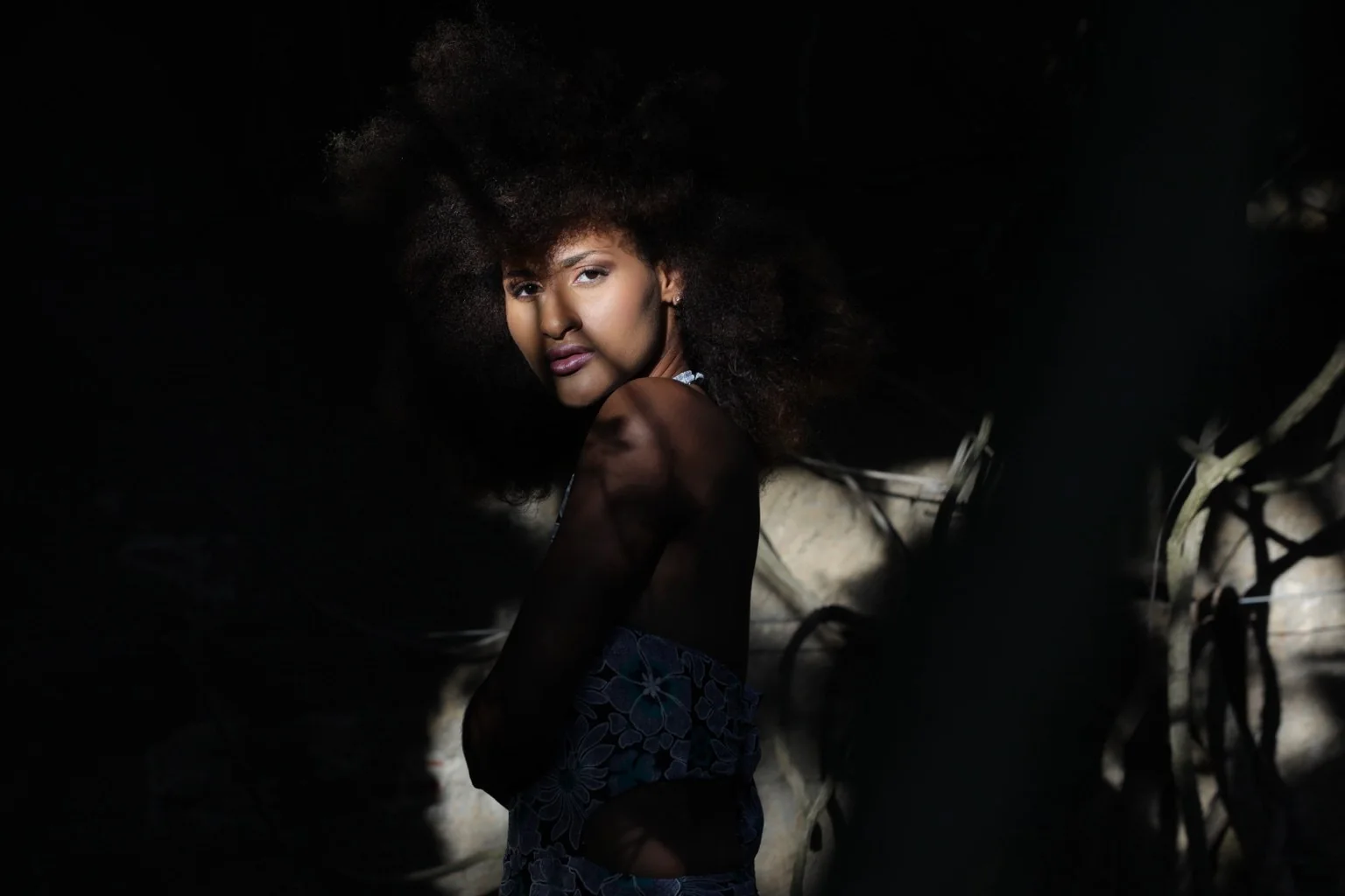 Modelo girada con vestido floral y luz entre las sombras.