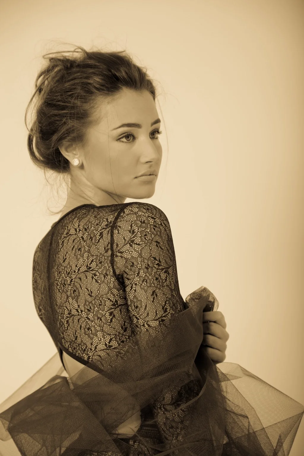 Retrato en tono sepia con encaje y tul, mirando sobre el hombro.