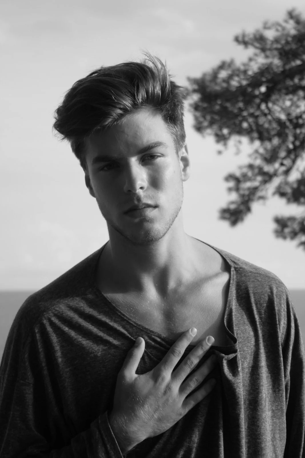 Retrato masculino en blanco y negro con la mano sobre el pecho.
