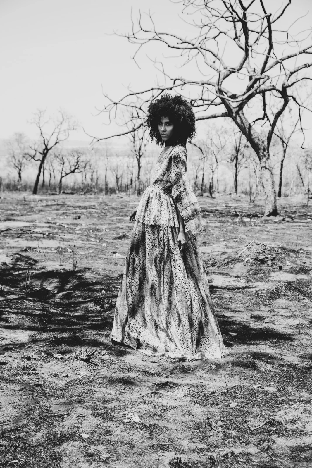Proyecto personal en blanco y negro: modelo con vestido largo en un paisaje de árboles.