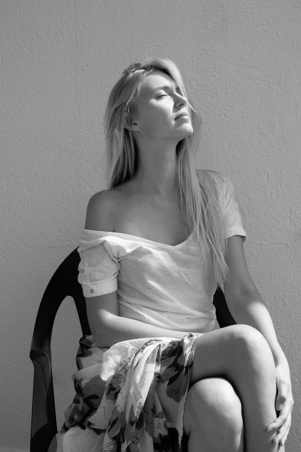 Modelo sentada con camisa blanca en una sesión en blanco y negro.