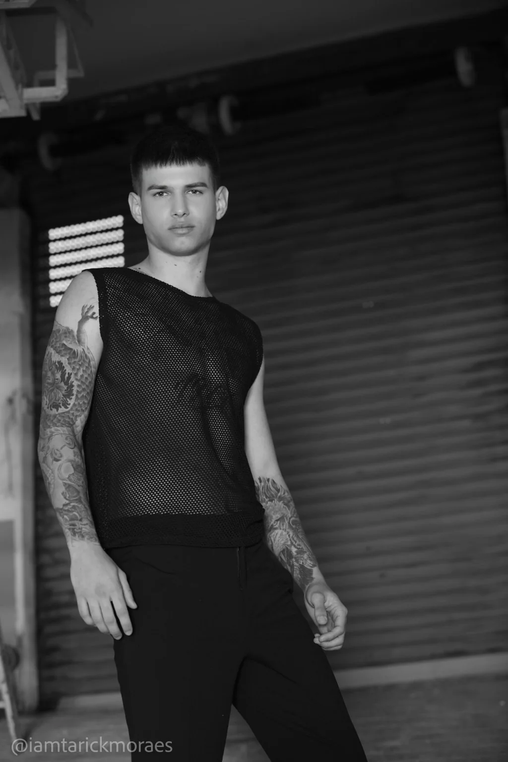 Modelo con camiseta negra de malla en un espacio industrial.