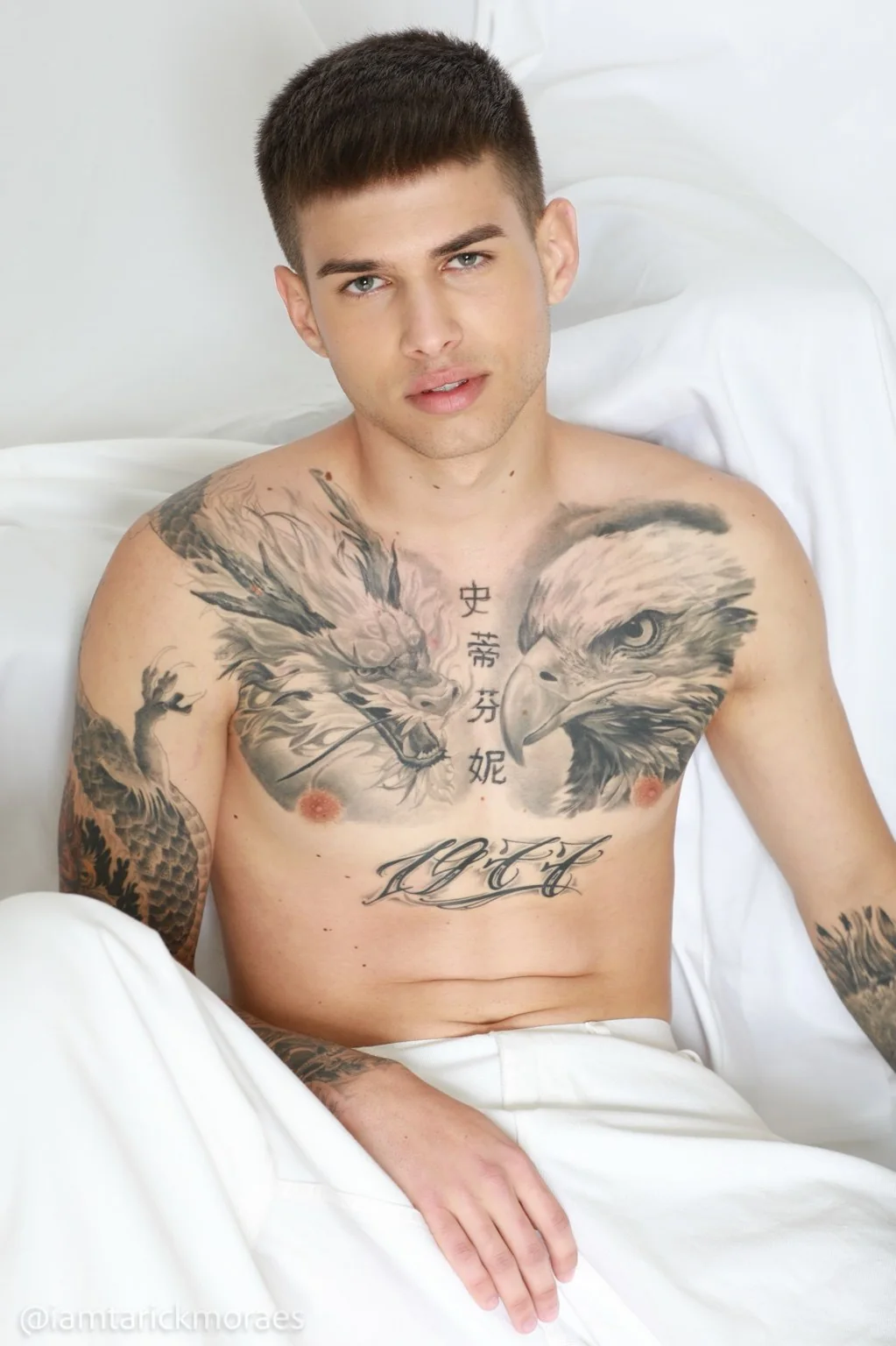 Retrato de un modelo sentado con pantalón blanco.